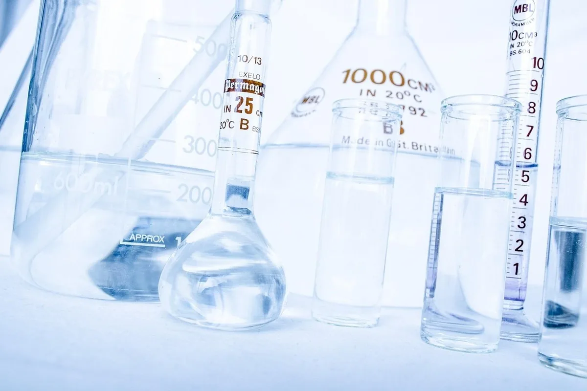Coenzyme Q10 au Maroc : cœur, énergie & tension 14 Verrerie de laboratoire et gélule de coenzyme Q10 ambrée sur fond clair, illustrant l'évaluation scientifique du CoQ10