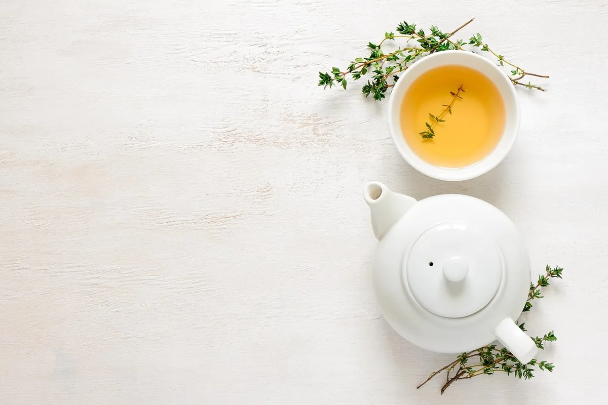 Personne tenant une tasse de tisane apaisante, geste évoquant l'apaisement d'un inconfort digestif