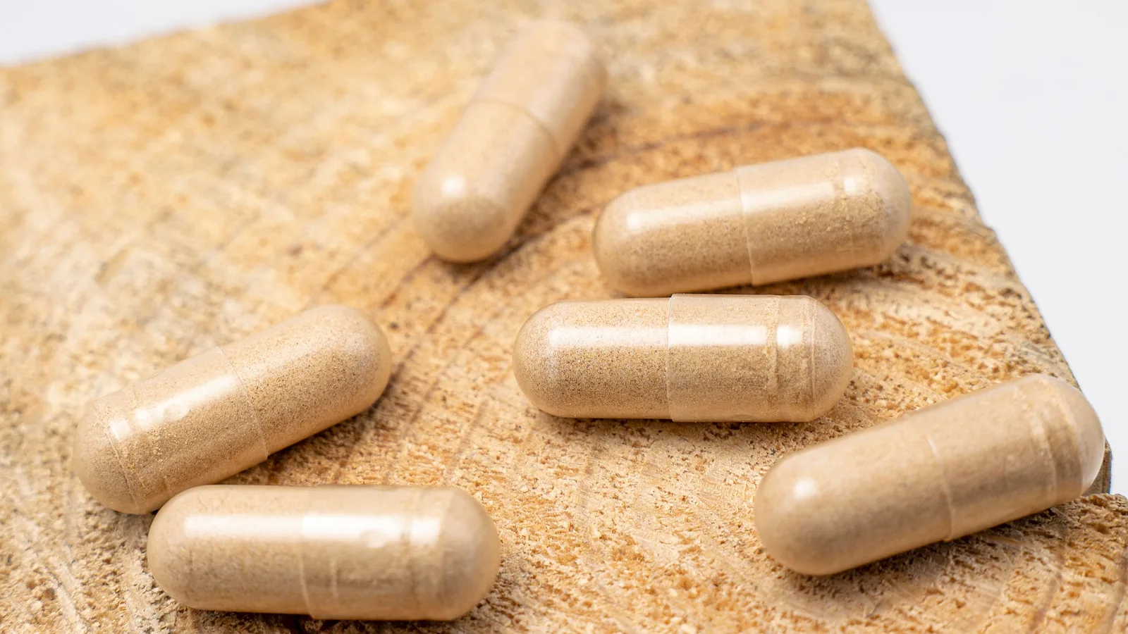 Levure de bière, sélénium & zinc : cheveux, ongles, peau — le décryptage 4 Gélules de levure de bière sur un support en bois clair – source de vitamines B, zinc et sélénium