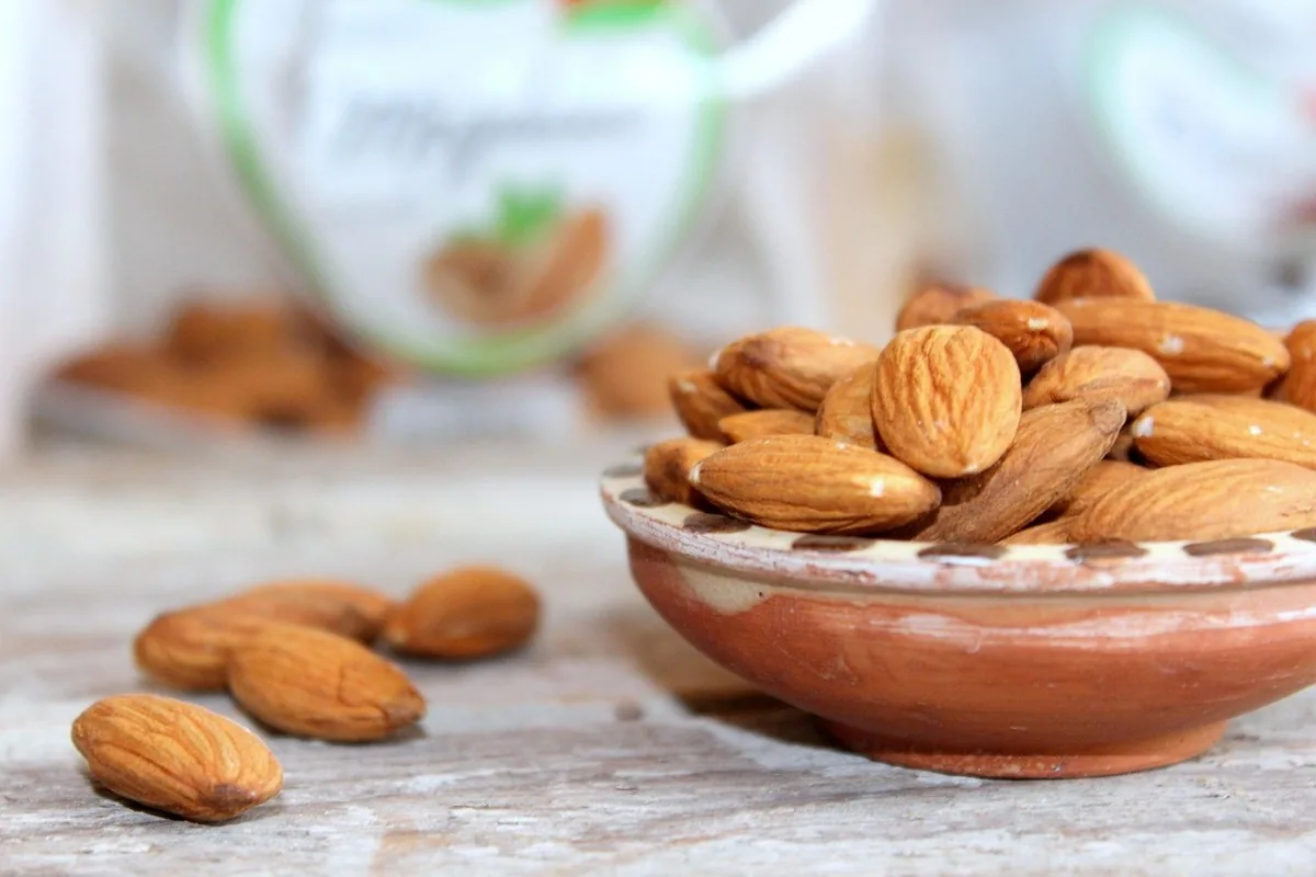 Morceaux de chocolat noir aux amandes dans un bol, sources naturelles de magnésium pour le calme nerveux