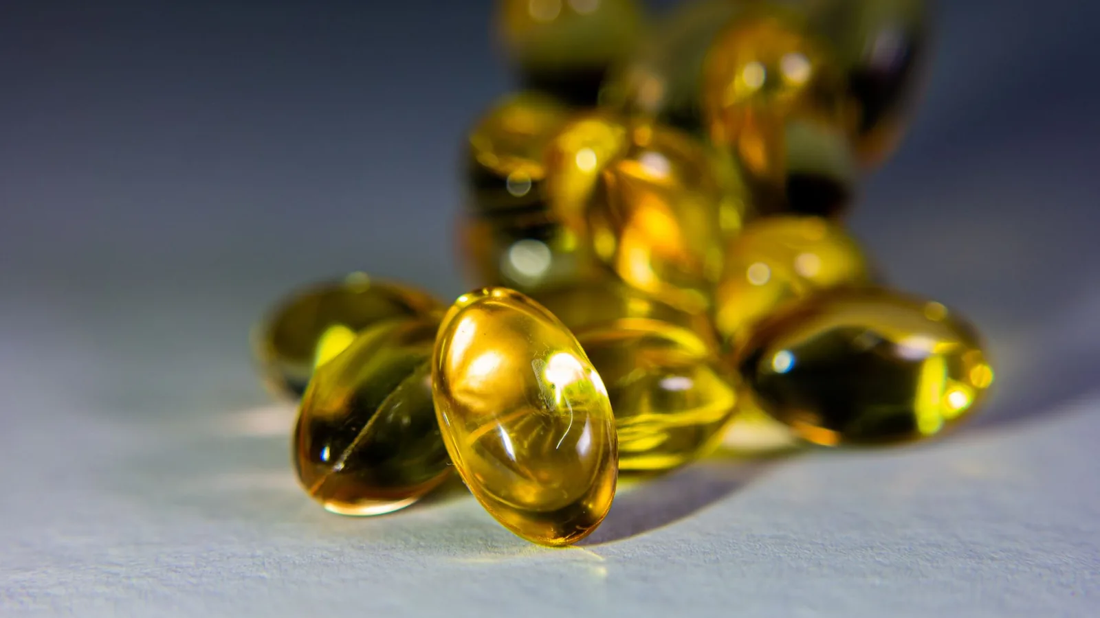 Vitamine D3 & K2 au Maroc : os, immunité & dosage — le décryptage 3 Capsules dorées de vitamine D3 et K2 sur fond clair – complément os et immunité